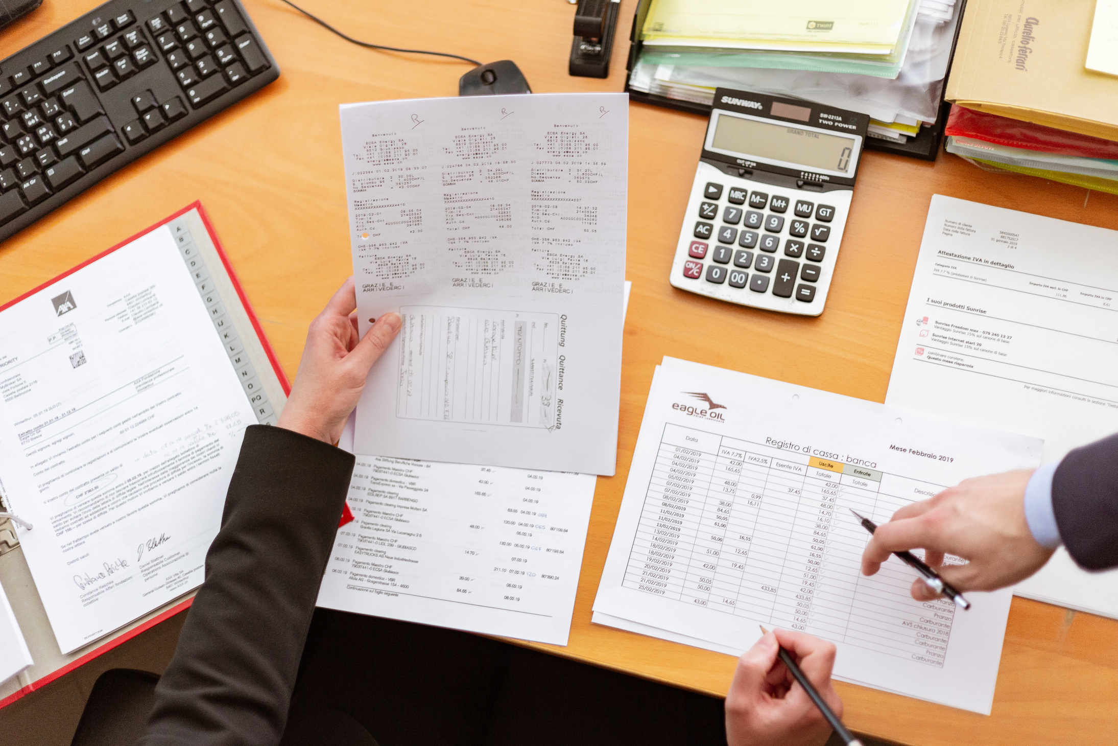 Person Holding Paper in Left Hand and Pen on Right Hand Sitting Beside Desk